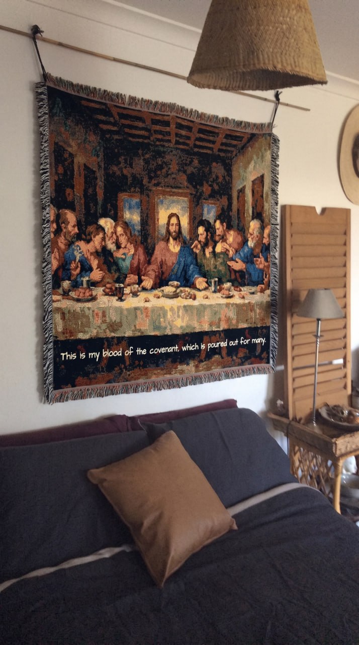 The Last Supper woven blanket hung as a wall tapestry above a bed